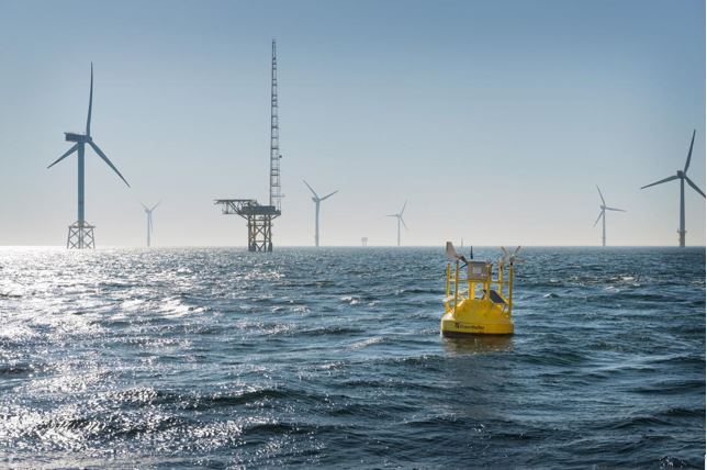 A floating LiDAR in front of a fixed met mast in an offshore wind farm. Photo: Frauenhofer IWES
